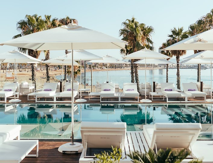 Pren un còctel a la piscina amb la posta de sol